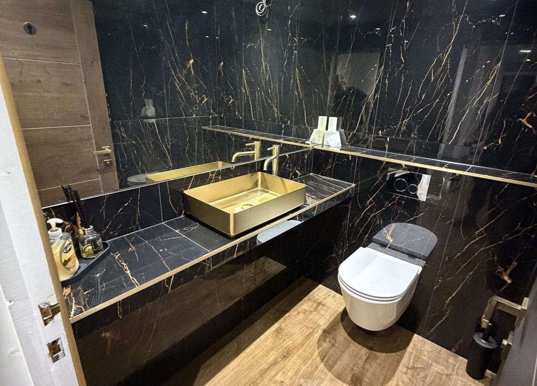 A finished bathroom in black marble with brushed gold fittings