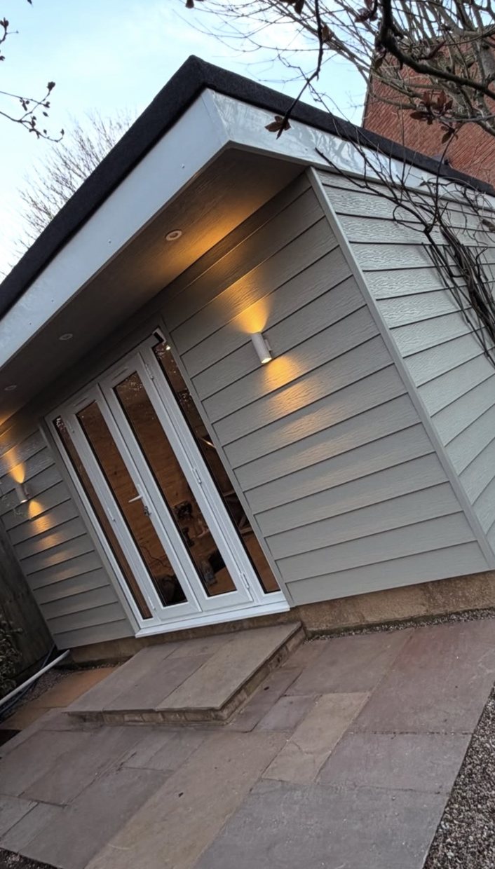 A completed Henry Daniel build in the evening, clad elevation with lit entrance